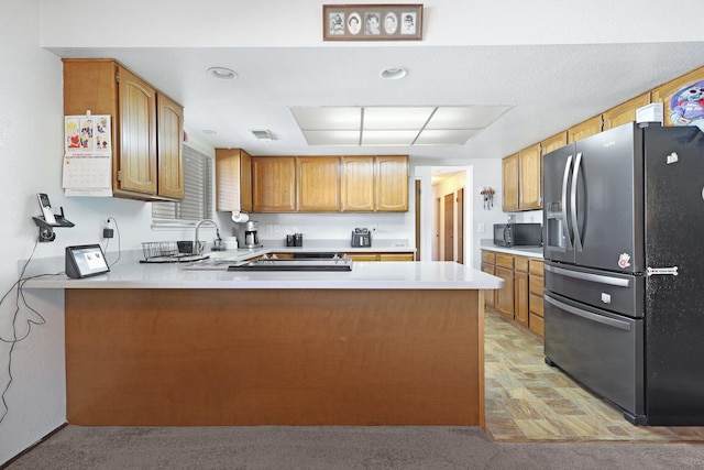 kitchen featuring stainless steel fridge, kitchen peninsula, sink, and light carpet