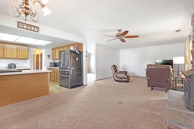 living room with light colored carpet, ceiling fan with notable chandelier, and a textured ceiling