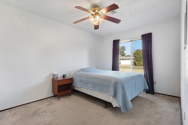 bedroom featuring ceiling fan, light colored carpet, and a textured ceiling