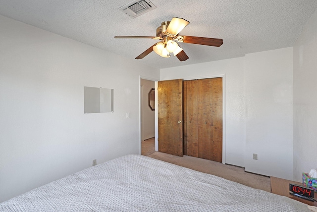 carpeted bedroom featuring ceiling fan, a closet, and a textured ceiling