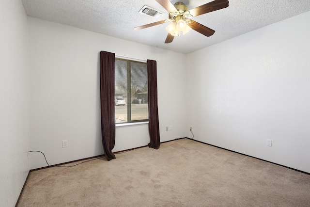 carpeted spare room featuring ceiling fan and a textured ceiling