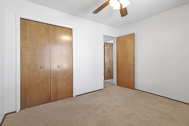 unfurnished bedroom featuring ceiling fan, light colored carpet, a closet, and a textured ceiling