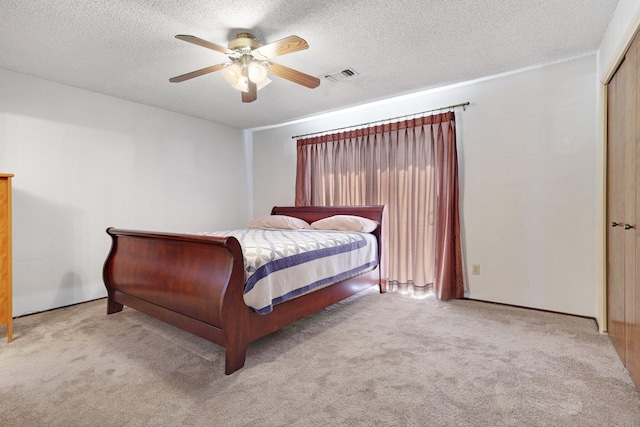 bedroom with ceiling fan, light colored carpet, a textured ceiling, and a closet