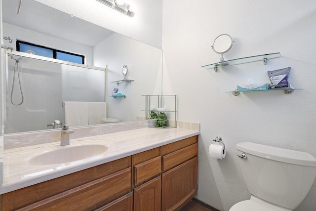 bathroom featuring vanity, a shower with shower door, and toilet