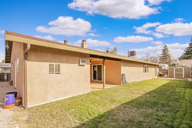 rear view of property featuring central air condition unit, a lawn, an AC wall unit, a storage unit, and a patio