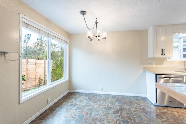 unfurnished dining area featuring a textured ceiling and a chandelier