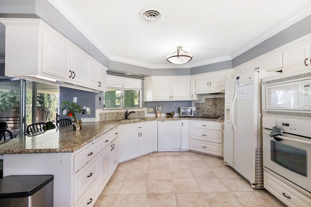 kitchen featuring white appliances, kitchen peninsula, dark stone counters, sink, and white cabinetry