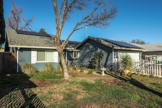 ranch-style home with a front yard, a garage, and solar panels