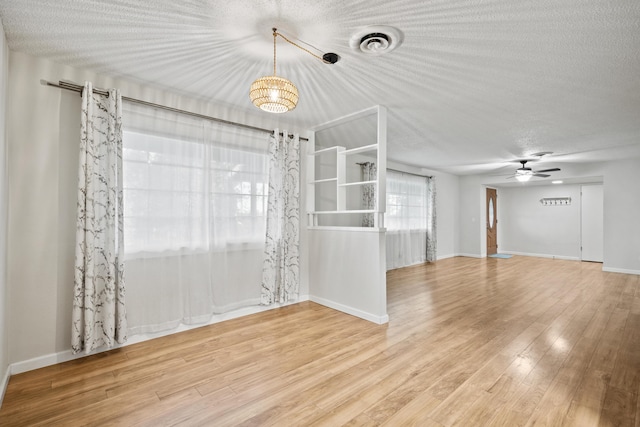 empty room with ceiling fan with notable chandelier and hardwood / wood-style floors