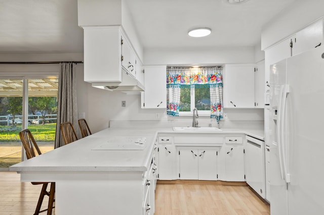 kitchen featuring white appliances, a breakfast bar, light wood-type flooring, white cabinets, and sink