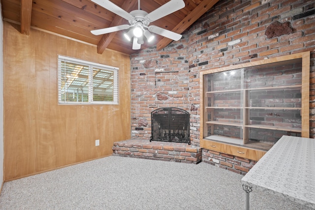 living room featuring vaulted ceiling with beams, ceiling fan, a brick fireplace, wood walls, and carpet floors