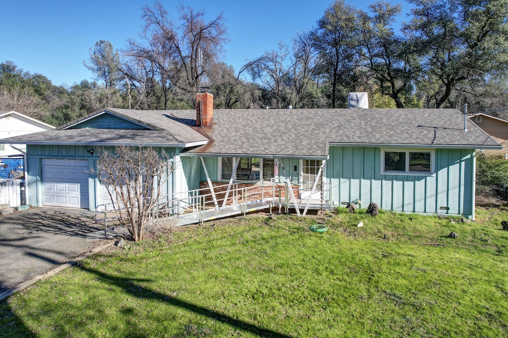 single story home featuring covered porch, a front lawn, and a garage