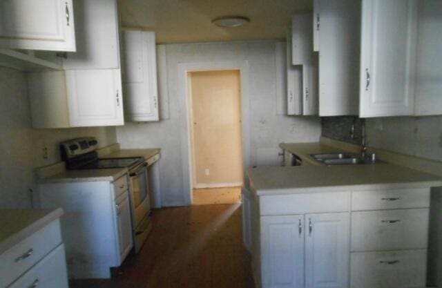 kitchen with sink, stainless steel electric range, and white cabinets