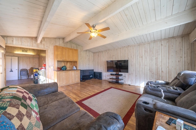 living room featuring hardwood / wood-style flooring, wood walls, ceiling fan, and vaulted ceiling with beams