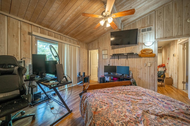 bedroom featuring vaulted ceiling, hardwood / wood-style flooring, wood walls, and ceiling fan