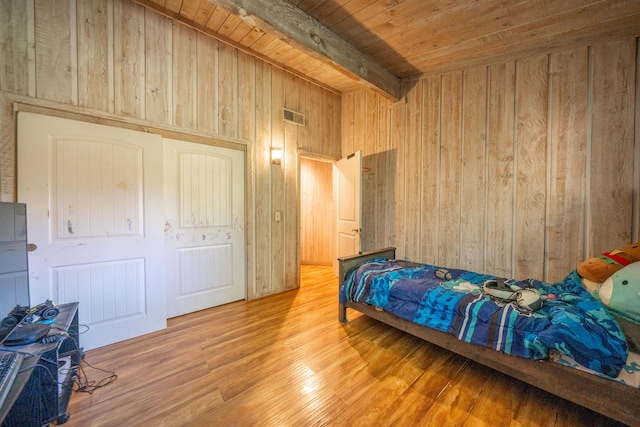 bedroom with hardwood / wood-style floors, wooden ceiling, wood walls, and beamed ceiling