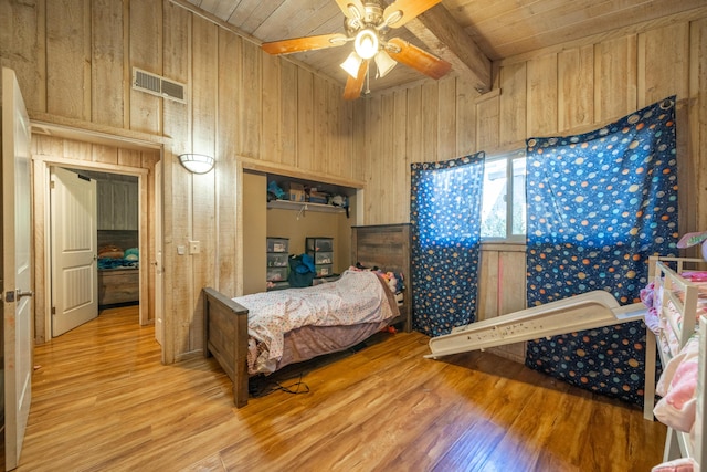 bedroom with ceiling fan, wood ceiling, wood walls, and beamed ceiling