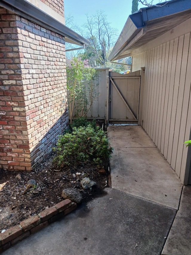 exterior space featuring brick siding and a gate