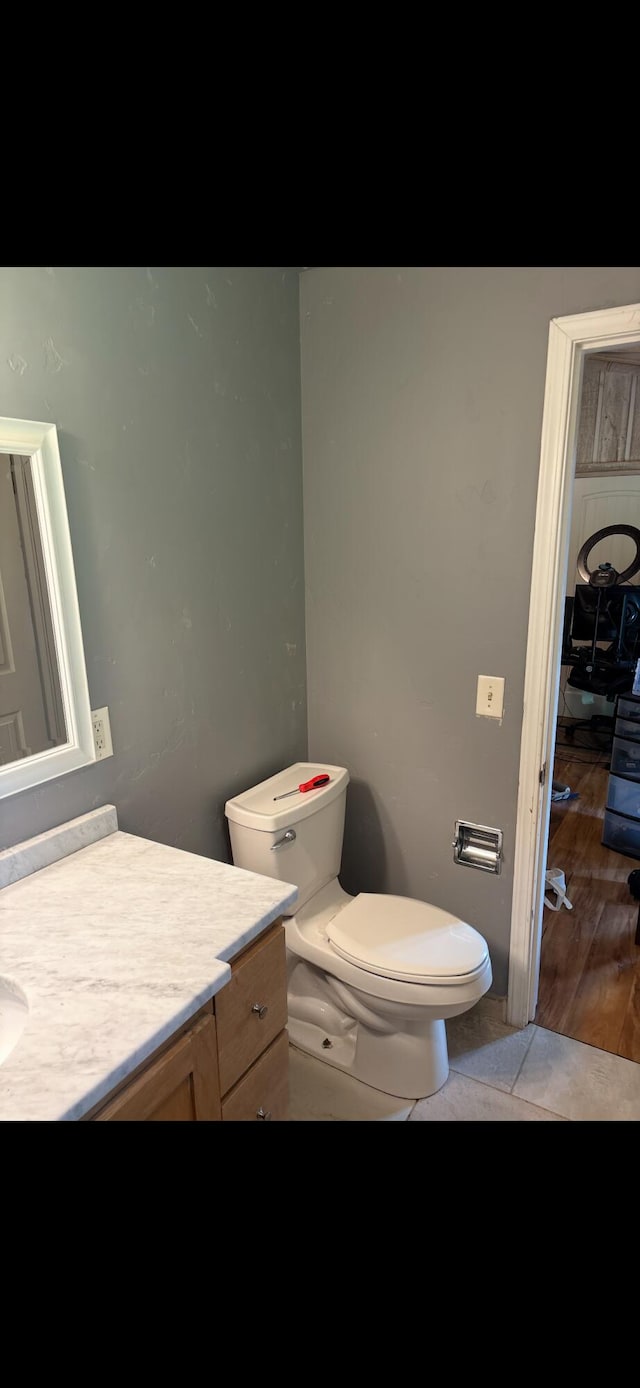 half bath with toilet, vanity, and wood finished floors