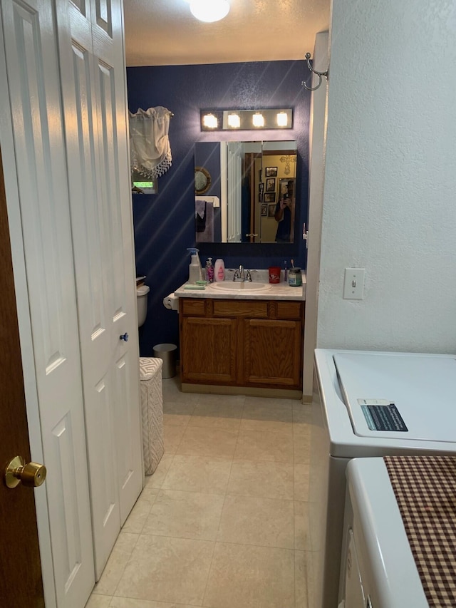 bathroom with tile patterned floors, washing machine and dryer, vanity, and toilet