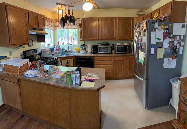 kitchen with kitchen peninsula, stainless steel appliances, light wood-type flooring, ceiling fan, and sink