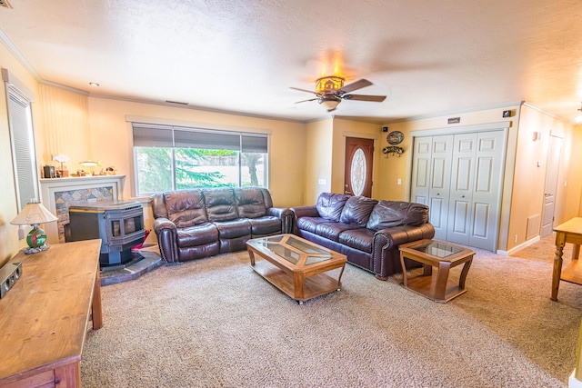 carpeted living room with a textured ceiling, ceiling fan, crown molding, and a wood stove