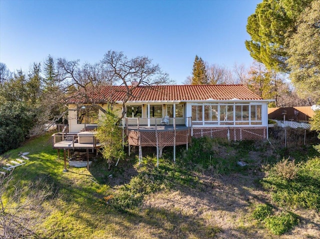 back of house with a deck, a sunroom, and a lawn