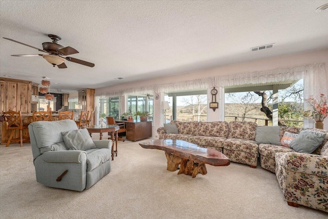 carpeted living room featuring a textured ceiling, ceiling fan, and a healthy amount of sunlight