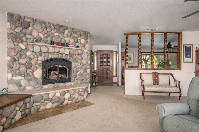 living room with light carpet, ceiling fan, a fireplace, and a textured ceiling