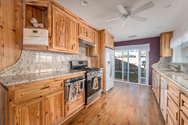 kitchen with tasteful backsplash, appliances with stainless steel finishes, sink, and light stone counters