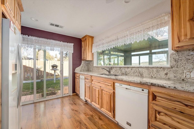 kitchen with a wealth of natural light, refrigerator with ice dispenser, sink, and white dishwasher