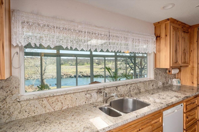 kitchen with a wealth of natural light, a water view, dishwasher, and sink