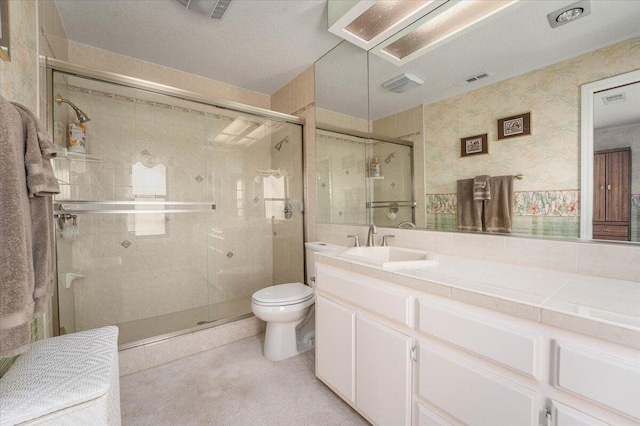 bathroom with an enclosed shower, vanity, toilet, and a textured ceiling