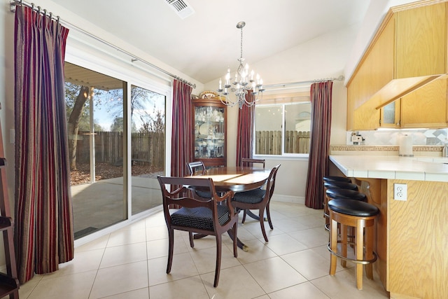 tiled dining space featuring lofted ceiling and a chandelier