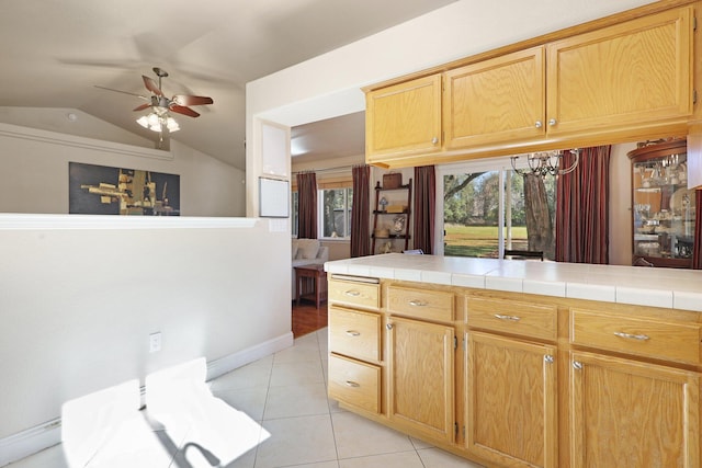 kitchen featuring ceiling fan, tile countertops, vaulted ceiling, and light tile patterned floors