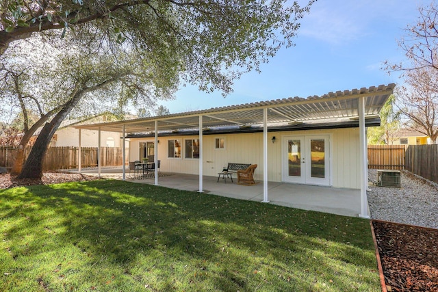 rear view of house featuring cooling unit, a patio area, french doors, and a lawn