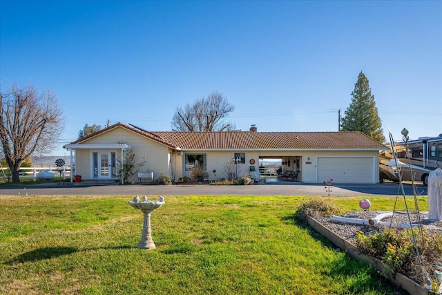 ranch-style house featuring a garage and a front lawn