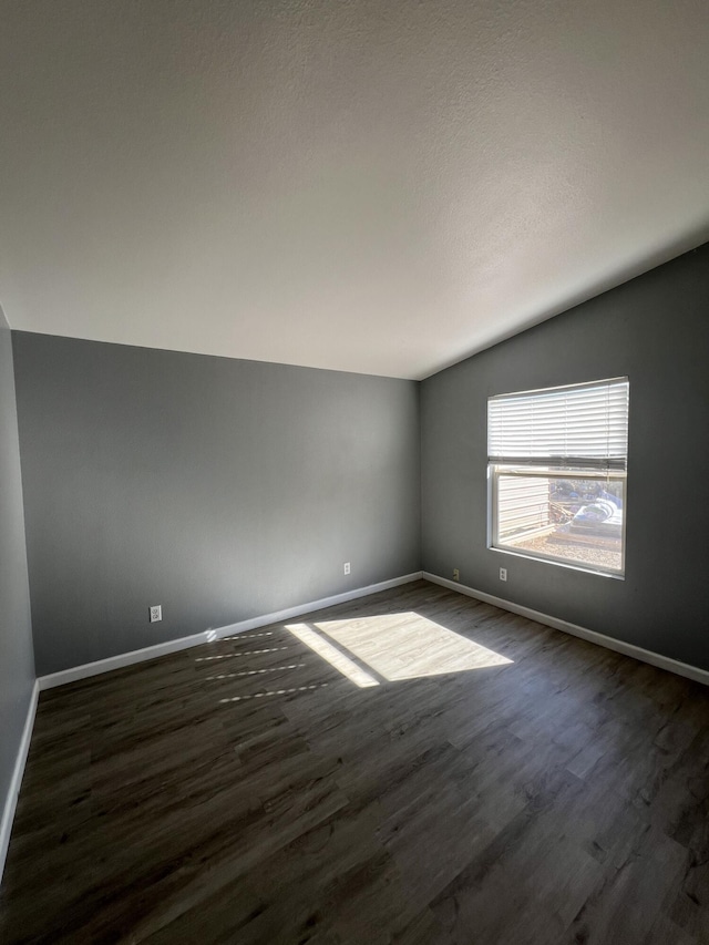 spare room with vaulted ceiling and dark hardwood / wood-style floors