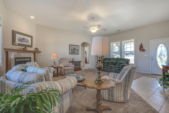 living room featuring a tiled fireplace, light tile patterned floors, and ceiling fan