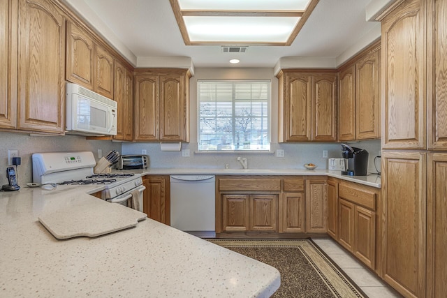 kitchen featuring white appliances, light stone countertops, sink, and light tile patterned floors