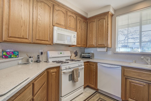 kitchen featuring light tile patterned flooring, sink, light stone counters, and white appliances