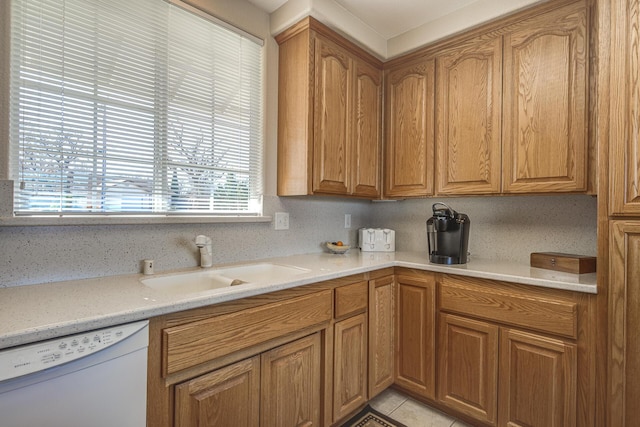 kitchen with light stone counters, white dishwasher, sink, and light tile patterned floors