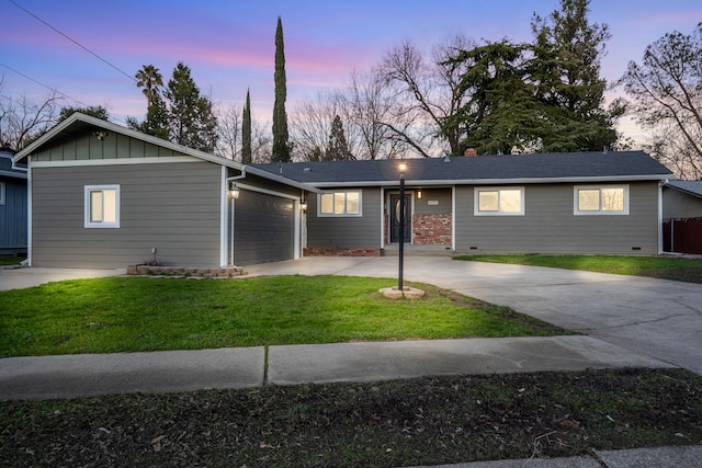 ranch-style home with a garage and a lawn