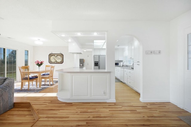 kitchen with white cabinetry, white appliances, and light hardwood / wood-style floors