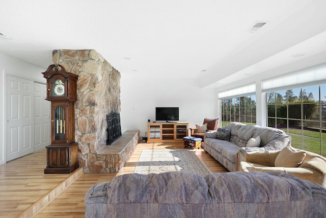 living room with a stone fireplace and light hardwood / wood-style floors