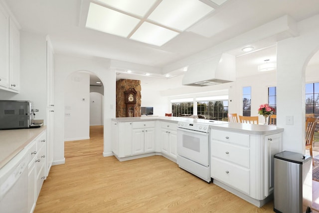 kitchen with white cabinets, custom exhaust hood, light hardwood / wood-style floors, kitchen peninsula, and white appliances