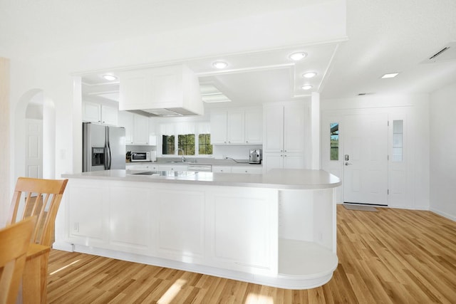 kitchen featuring stainless steel refrigerator with ice dispenser, white cabinetry, a large island, and light hardwood / wood-style floors