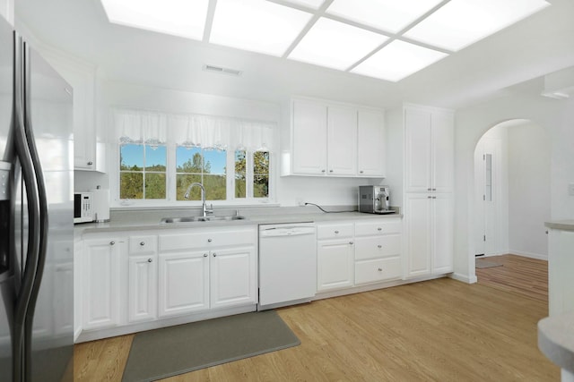 kitchen with sink, white appliances, white cabinets, and light wood-type flooring