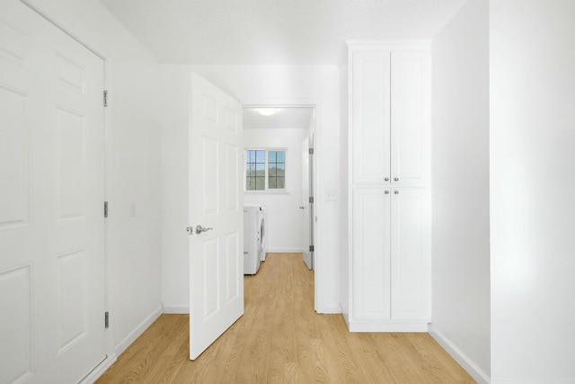 hallway with separate washer and dryer and light hardwood / wood-style floors