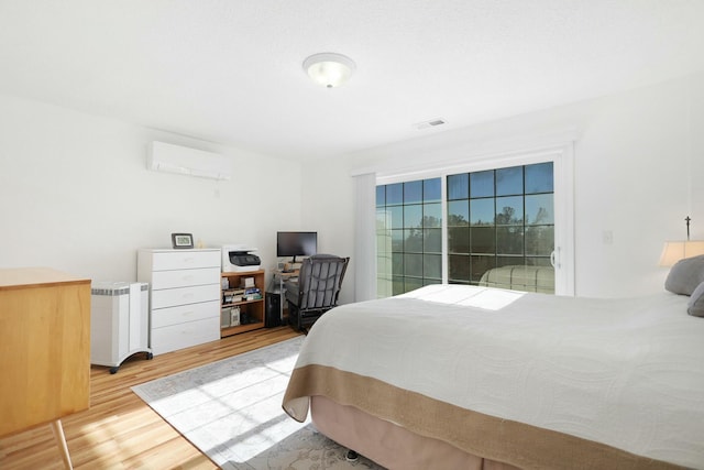 bedroom featuring a wall mounted AC and light wood-type flooring